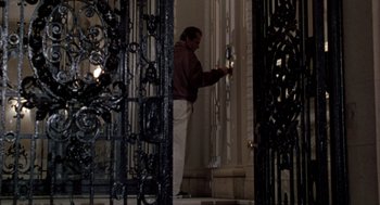Movie still from “Wolf” (1994), directed by Mike Nichols – A man standing in front of an ornate iron gate; Wide shot, High angle