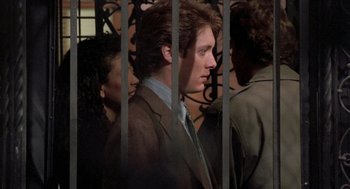 Movie still from “Wolf” (1994), directed by Mike Nichols – A man standing in front of two other men behind bars; Close Up shot, Over the shoulder angle