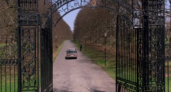 Movie still from “Wolf” (1994), directed by Mike Nichols – A car driving down a road through a gate; Extreme Wide shot, High angle