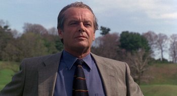Movie still from “Wolf” (1994), directed by Mike Nichols – A man in a suit and tie standing in front of trees; Close Up shot, Low angle