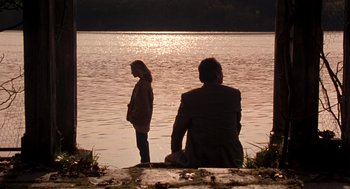 Movie still from “Wolf” (1994), directed by Mike Nichols – A man and a woman sitting on the shore of a lake; Wide shot, Over the shoulder angle