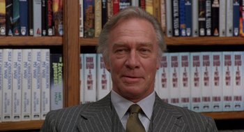 Movie still from “Wolf” (1994), directed by Mike Nichols – An older man wearing a suit and tie in front of a book shelf; Close Up shot, Low angle
