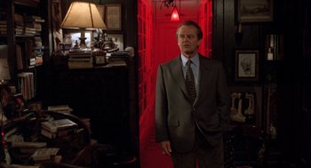 Movie still from “Wolf” (1994), directed by Mike Nichols – A man in a suit standing in front of a red door; Wide shot, Low angle