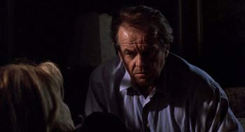 Movie still from “Wolf” (1994), directed by Mike Nichols – An older man sitting in front of a woman in a dark room; Close Up shot, Over the shoulder angle