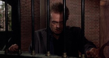 Movie still from “Wolf” (1994), directed by Mike Nichols – A man in a black jacket behind bars; Medium shot, High angle