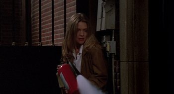Movie still from “Wolf” (1994), directed by Mike Nichols – A woman holding a fire extinguisher while standing next to a building; Medium shot, Over the shoulder angle