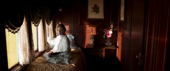 Movie still from “Woman Walks Ahead” (2017), directed by Susanna White – A little girl sitting on a bed in a bedroom; Medium shot, High angle