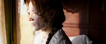 Movie still from “Woman Walks Ahead” (2017), directed by Susanna White – A young woman with long red hair wearing a white shirt; Close Up shot, Low angle
