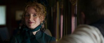 Movie still from “Woman Walks Ahead” (2017), directed by Susanna White – A person with curly hair wearing a dress; Close Up shot, Over the shoulder angle