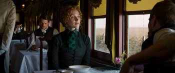 Movie still from “Woman Walks Ahead” (2017), directed by Susanna White – A woman sitting at a table with a plate of food; Medium shot, Over the shoulder angle