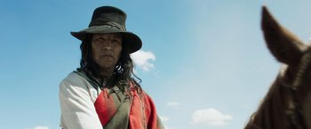 Movie still from “Woman Walks Ahead” (2017), directed by Susanna White – An older man wearing a green hat and a red blanket; Medium shot, Low angle