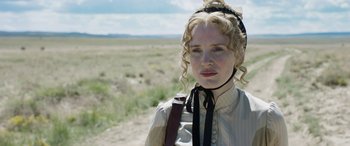 Movie still from “Woman Walks Ahead” (2017), directed by Susanna White – A woman with blonde curly hair wearing a white dress; Close Up shot, Low angle