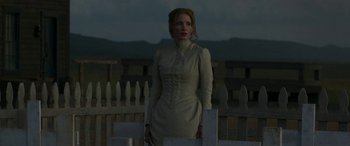 Movie still from “Woman Walks Ahead” (2017), directed by Susanna White – A woman standing in front of a white picket fence at night; Medium shot, Low angle