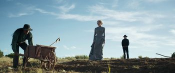 Movie still from “Woman Walks Ahead” (2017), directed by Susanna White – A woman standing in a field next to a man; Wide shot, Low angle
