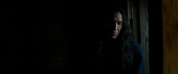 Movie still from “Woman Walks Ahead” (2017), directed by Susanna White – A man with long black hair is looking into the dark; Close Up shot, Low angle