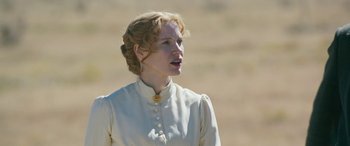 Movie still from “Woman Walks Ahead” (2017), directed by Susanna White – A woman in a white dress standing in a field; Close Up shot, Low angle