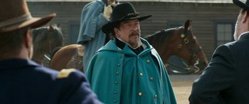Movie still from “Woman Walks Ahead” (2017), directed by Susanna White – A man wearing a green cape and a black hat; Medium shot, Over the shoulder angle