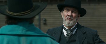 Movie still from “Woman Walks Ahead” (2017), directed by Susanna White – An older man wearing a suit and a hat; Close Up shot, Over the shoulder angle