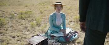 Movie still from “Woman Walks Ahead” (2017), directed by Susanna White – A woman sitting on the ground in a field; Wide shot, High angle