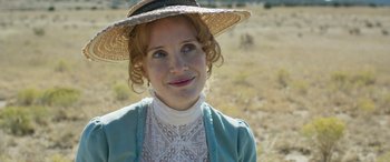 Movie still from “Woman Walks Ahead” (2017), directed by Susanna White – A woman in a straw hat standing in a field; Close Up shot, Over the shoulder angle