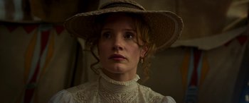 Movie still from “Woman Walks Ahead” (2017), directed by Susanna White – A woman wearing a straw hat and a white dress; Close Up shot, Low angle