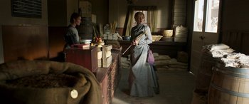 Movie still from “Woman Walks Ahead” (2017), directed by Susanna White – A woman in a long gray dress holding a stick; Medium shot, Over the shoulder angle