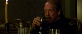 Movie still from “Woman Walks Ahead” (2017), directed by Susanna White – A person holding a glass of wine; Close Up shot, Over the shoulder angle
