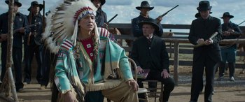 Movie still from “Woman Walks Ahead” (2017), directed by Susanna White – A man in a native american outfit sitting on a chair; Medium shot, Over the shoulder angle