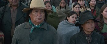 Movie still from “Woman Walks Ahead” (2017), directed by Susanna White – A group of people standing in a crowd wearing blankets; Close Up shot, Over the shoulder angle