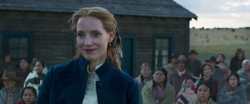 Movie still from “Woman Walks Ahead” (2017), directed by Susanna White – A group of people standing in front of a building; Close Up shot, Over the shoulder angle