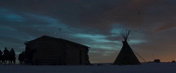 Movie still from “Woman Walks Ahead” (2017), directed by Susanna White – Two native american buildings in the snow at night; Extreme Wide shot, Low angle