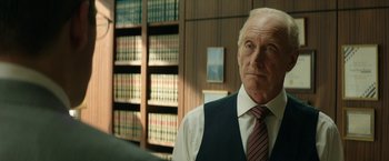 Movie still from “Woman in Gold” (2015), directed by Simon Curtis – An older man in a suit and tie in front of a book case; Close Up shot, Over the shoulder angle