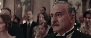 Movie still from “Woman in Gold” (2015), directed by Simon Curtis – An old man with a mustache and a mustache stand in front of a group of people; Close Up shot, Low angle
