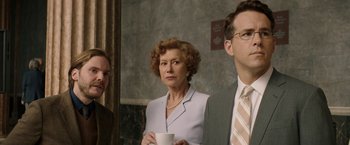 Movie still from “Woman in Gold” (2015), directed by Simon Curtis – A woman holding a coffee cup standing next to two other people; Medium shot, Over the shoulder angle