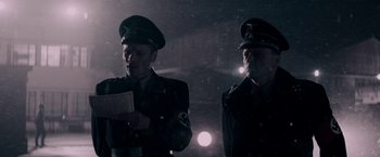 Movie still from “Woman in Gold” (2015), directed by Simon Curtis – Two men dressed in nazi uniforms stand in the dark; Medium shot, Low angle