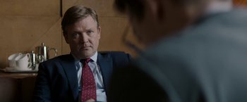 Movie still from “Woman in Gold” (2015), directed by Simon Curtis – A man wearing a suit and tie sitting in front of another man wearing a suit; Close Up shot, Over the shoulder angle