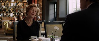 Movie still from “Woman in Gold” (2015), directed by Simon Curtis – An older woman sitting at a table in front of a vase of flowers; Medium shot, Over the shoulder angle