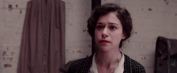 Movie still from “Woman in Gold” (2015), directed by Simon Curtis – A young woman with dark curly hair wearing a black and white suit; Close Up shot, Over the shoulder angle