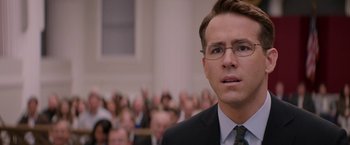 Movie still from “Woman in Gold” (2015), directed by Simon Curtis – A man in a suit and tie in front of an audience; Close Up shot, Over the shoulder angle