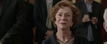 Movie still from “Woman in Gold” (2015), directed by Simon Curtis – An older woman wearing a black suit and pearl necklace; Close Up shot, Over the shoulder angle