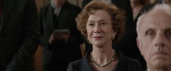 Movie still from “Woman in Gold” (2015), directed by Simon Curtis – An older woman wearing a black suit and pearl necklace; Close Up shot, Over the shoulder angle