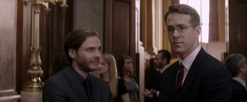 Movie still from “Woman in Gold” (2015), directed by Simon Curtis – A man in a suit standing next to another man in a suit; Medium shot, Over the shoulder angle