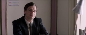 Movie still from “Woman in Gold” (2015), directed by Simon Curtis – A man wearing a suit and tie sitting in a room; Close Up shot, Over the shoulder angle