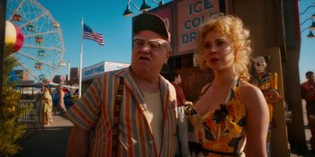 Movie still from “Wonder Wheel” (2017), directed by Woody Allen – An older man and a younger woman standing in front of an ice cold drink stand; Medium shot, Low angle