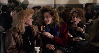 Movie still from “Working Girl” (1988), directed by Mike Nichols – A group of women sitting around a cake with candles; Medium shot, High angle