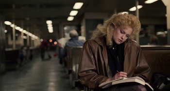 Movie still from “Working Girl” (1988), directed by Mike Nichols – A woman sitting on a bench writing in a notebook; Medium shot, High angle