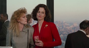 Movie still from “Working Girl” (1988), directed by Mike Nichols – Two women standing next to each other holding a glass; Medium shot, Over the shoulder angle