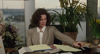 Movie still from “Working Girl” (1988), directed by Mike Nichols – A woman sitting at a desk in an office setting; Medium shot, Over the shoulder angle