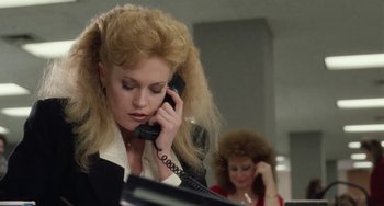 Movie still from “Working Girl” (1988), directed by Mike Nichols – A woman talking on a phone while another woman looks on; Close Up shot, Over the shoulder angle