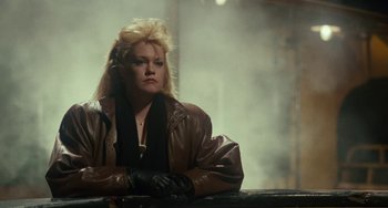 Movie still from “Working Girl” (1988), directed by Mike Nichols – A woman wearing a leather jacket and gloves; Medium shot, Low angle